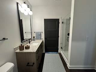 Bathroom with granite vanity and glass enclosed shower at The Wren Apartments, Lawrenceville, 30043