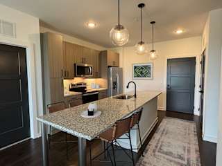 Kitchen with island seating and dark wood flooring at The Wren Apartments, Lawrenceville, GA