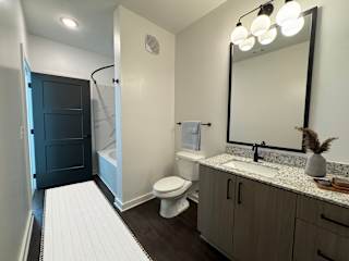 Bathroom with granite countertop and dark wood vanity at The Wren Apartments, Lawrenceville, Georgia