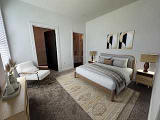 Bedroom with lounge chair and neutral tones at The Wren Apartments, Georgia