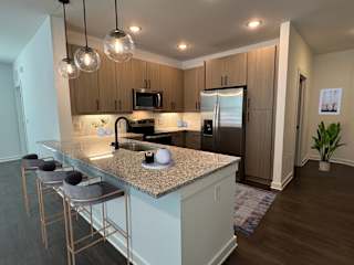 Kitchen island with bar stools and pendant lights at The Wren Apartments, Lawrenceville, 30043