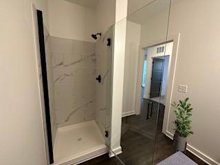 Walk in shower with marble tile and glass enclosure at The Wren Apartments, Lawrenceville