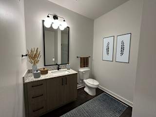 Powder room with framed mirror and botanical artwork at The Wren Apartments, Lawrenceville, GA