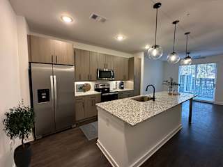 Modern kitchen with white island and globe pendant lights at The Wren Apartments, Lawrenceville, GA 30043