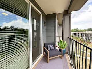 Covered balcony with chair and decorative plant at The Wren Apartments, Georgia, 30043
