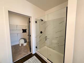 Ensuite bathroom with walk-in closet and frameless glass shower at The Wren Apartments, Georgia