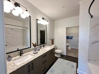 Dual sink vanity with speckled countertop and mirror at The Wren Apartments, Lawrenceville, Georgia