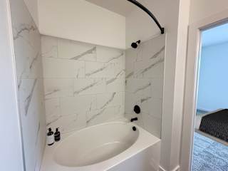 Bathtub with marble surround and curved shower rod at The Wren Apartments, Georgia