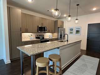 A kitchen with a granite countertop and wooden stools at The Wren Apartments, Georgia