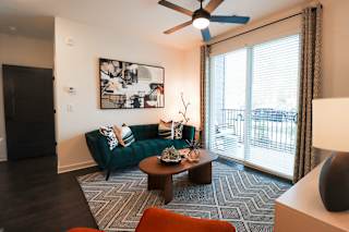 Living room with tufted emerald sofa and patterned rug at The Wren Apartments, Lawrenceville