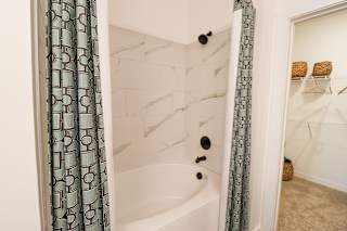 Tub shower combo with marble tile surround at The Wren Apartments, Georgia, 30043