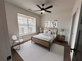 A bedroom with a bed, chair, and ceiling fan. at The Wren Apartments, Lawrenceville , GA, 30043