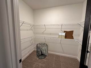A small, empty room with a carpeted floor and a metal waste basket at The Wren Apartments, Lawrenceville , Georgia