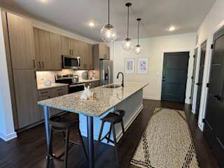 Modern kitchen with island seating and wood cabinetry at The Wren Apartments, Lawrenceville