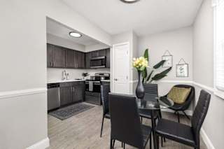 A kitchen with a dining table and chairs.