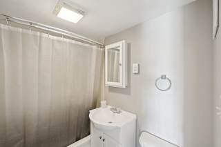 A white bathroom with a sink, toilet and shower curtain.
