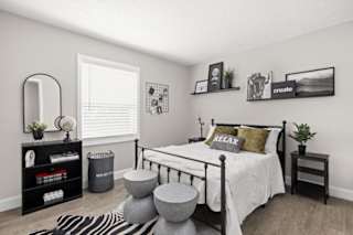 A bedroom with a bed, nightstand, and a mirror.