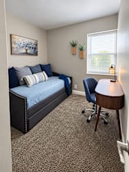 A bedroom with a bed, desk, and chair.