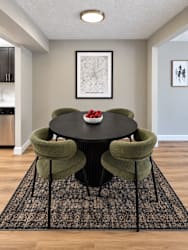 A dining room with a black table and green chairs.