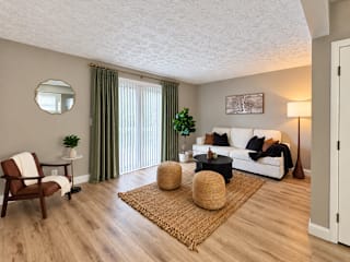A living room with a white couch, a wooden chair, and a round mirror on the wall.