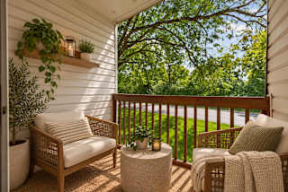 A white chair with a striped pillow sits on a porch.