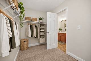 A white door is open to a room with a white wall and a wooden floor.