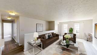 A modern living room with a brown couch and a glass coffee table.