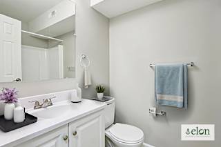 A white bathroom with a toilet, sink, and mirror.