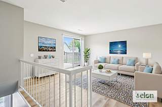 A living room with a white couch and a painting on the wall.