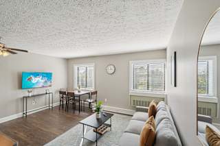 A living room with a grey couch and a painting on the wall.