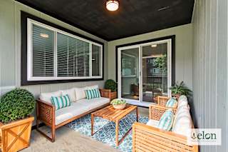 A patio with a couch, chairs, and a table with a bowl of fruit on it.