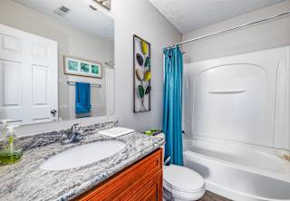 A bathroom with a marble countertop and a white bathtub.