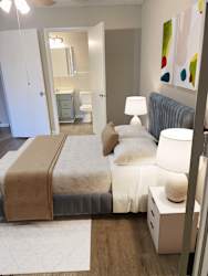 A bedroom with a bed, nightstand, and lamp. at Aqua Bay Apartments in Naples, FL 34116