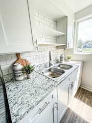 A kitchen with a marble countertop and white cabinets.