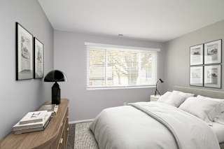 A bedroom with a bed, nightstand, and pictures on the wall.