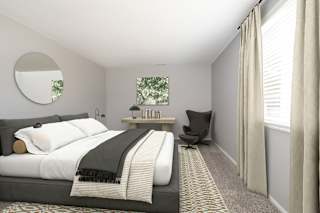 A bedroom with a large bed and a chair.