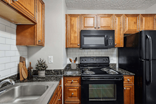 A kitchen with black appliances and wooden cabinets.