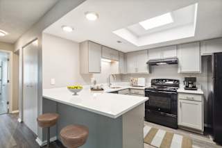 A kitchen with a white counter top and brown stools.