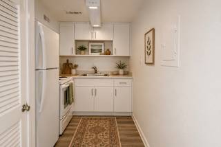 A kitchen with white cabinets and a rug on the floor.