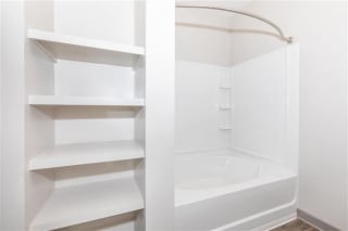 Bathroom with tub and empty shelves at One White Oak Apartments, Georgia