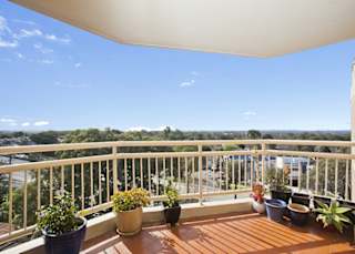 a balcony with potted plants and a view of the city