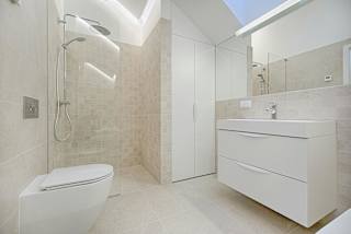 A white bathroom with a toilet, sink, and shower.