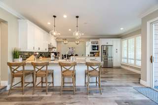 A kitchen with a white counter top and wooden chairs.