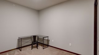 Furnished apartment den with work desk and chair in corner of room