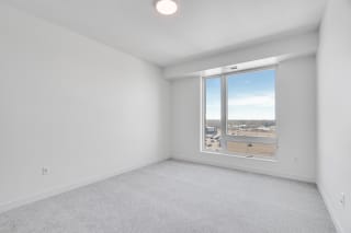 TheRowanLuxuryApartments Spacious carpeted bedroom with large window allowing a lot of natural light in at The Rowan apartments in Eagan Minnesota