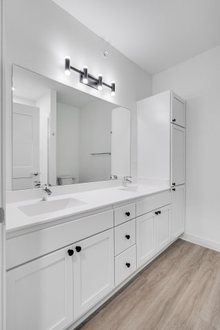 TheRowanLuxuryApartments Bathroom with white double vanity and linen cabinet for storage and large mirror at The Rowan in Eagan Minnesota