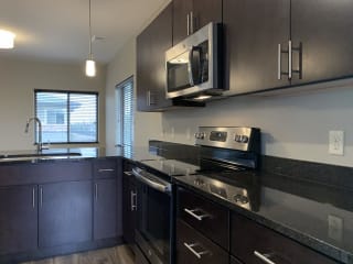 Dark brown kitchen cabinets with matching stainless steel appliances at the villas at mahoney park