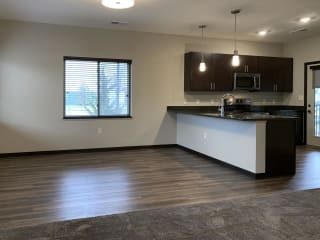 Dining next to kitchen with hard wood style flooring at the villas at mahoney park