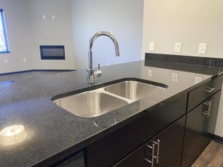 large granite counter with double sided sink in the kitchen of the acadia floorplan