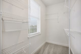 a closet with white walls and a window in a room with white closets